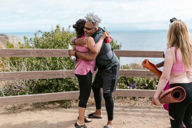 A group of diverse friends hugging after an outdoor yoga session by the sea.