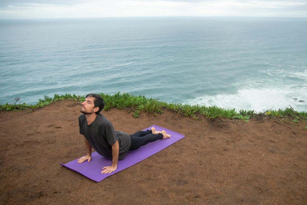 A man doing yoga on a cliffside overlooking the ocean in Portugal.
