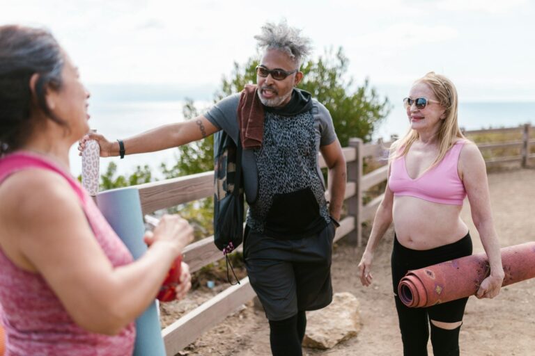 Senior adults enjoy a sunny day outdoors practicing yoga together, promoting wellness and community.